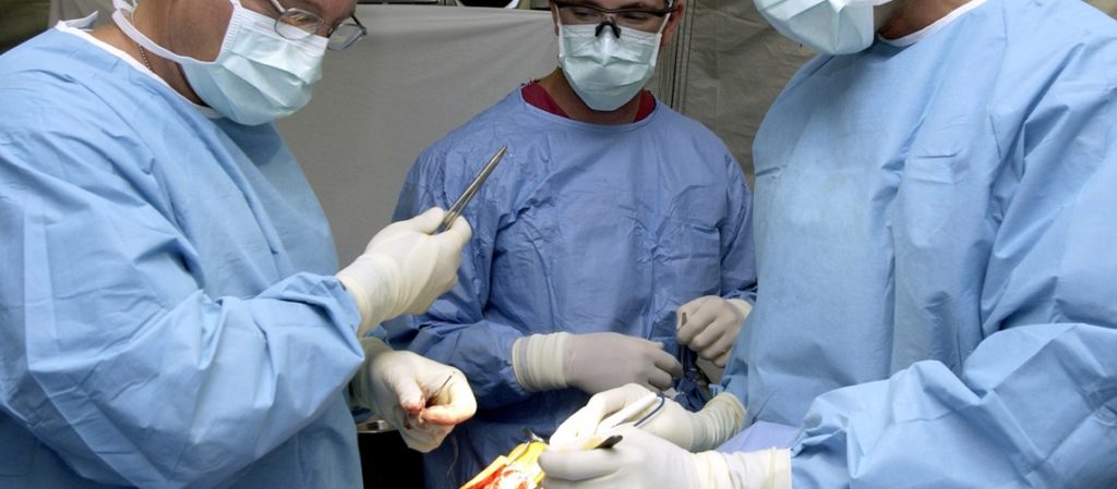 U.S. Air Force surgeons Dr. Patrick Miller (left), Dr. Michael Hughes (right), and surgical technician SrA Ray Wilson from the 379th Expeditionary Medical Squadron, repair the ruptured achilles tendon of a servicemember on March 11, 2003. The doctors are performing this surgey at a field hospital in a foward-deployed location. (U.S. Air Force photo by SSgt. DERRICK C. GOODE)(RELEASED)